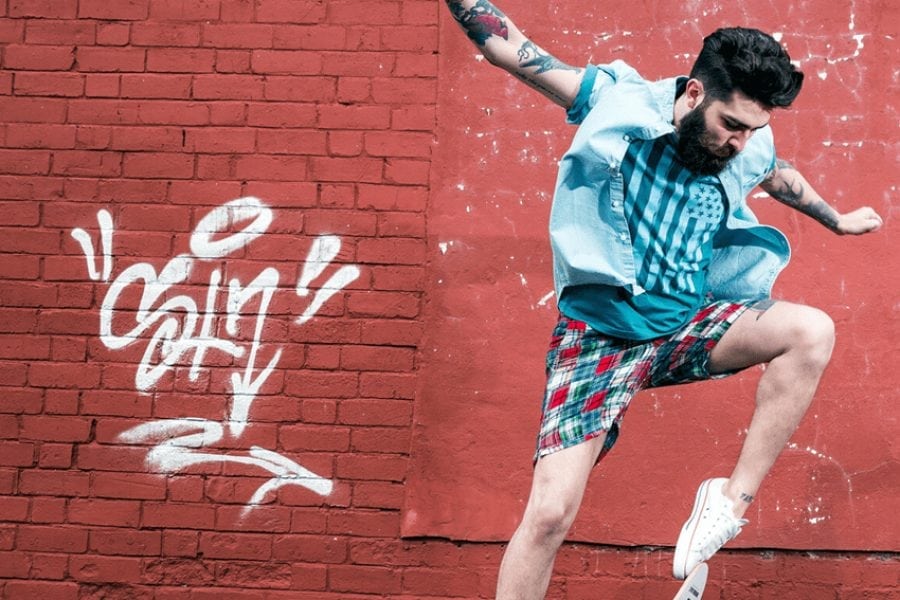 Man doing a skateboard trick in front of a wall with graffiti on it