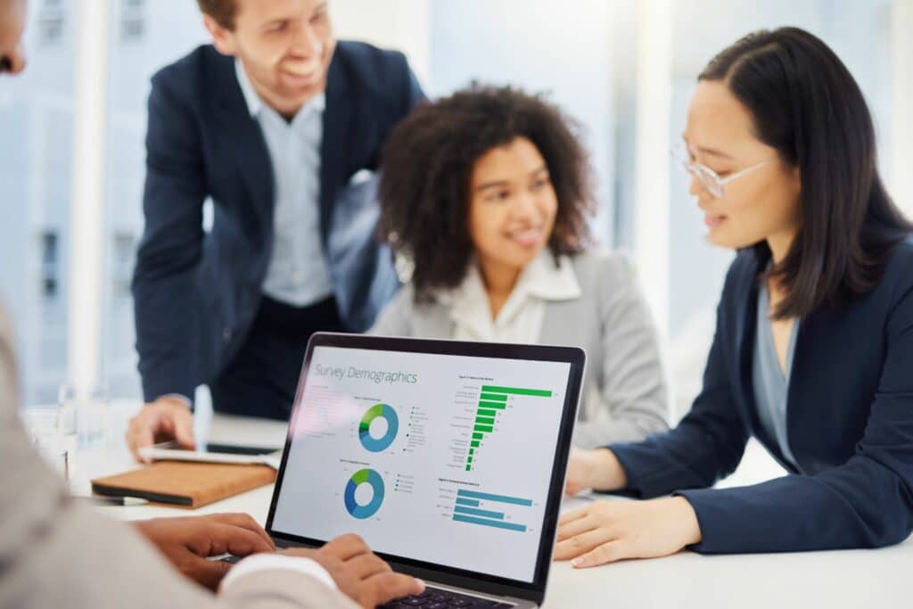 person working on stats and in background three people are discussing