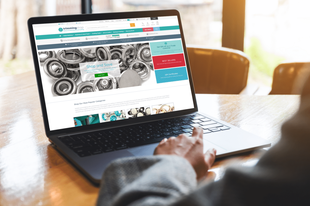 Person using a laptop viewing Trimming Shop website on screen