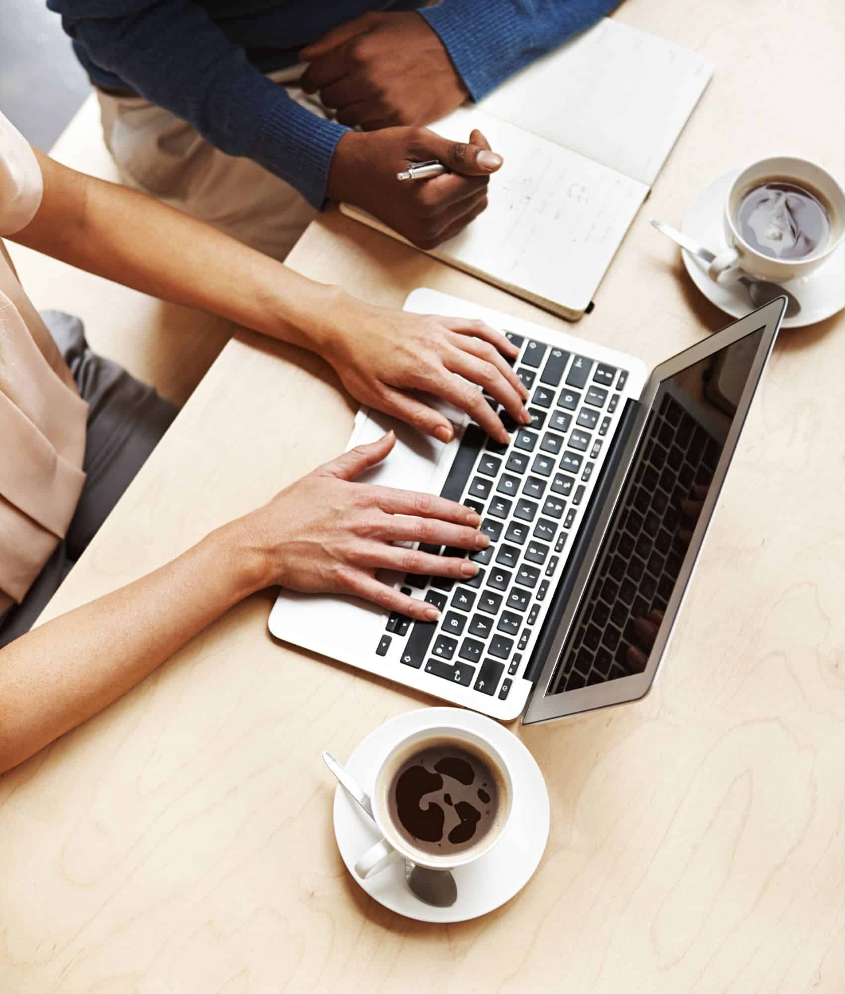 two people working on laptop and notebook